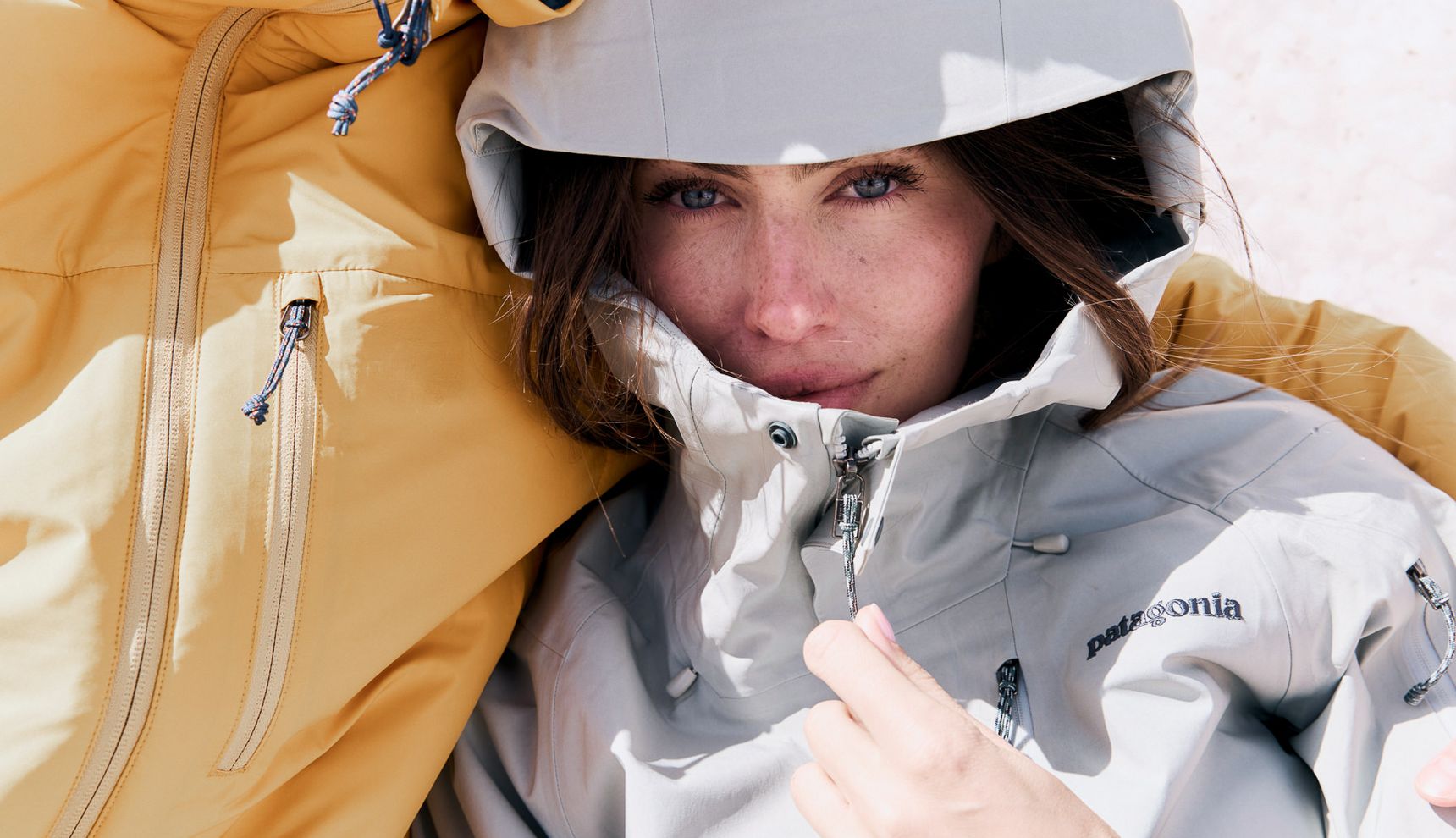 Woman in a grey winter jacket in her partner's arms in the snow