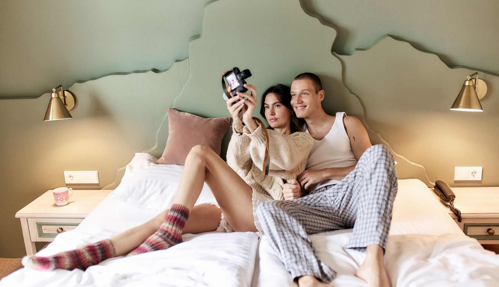 Couple in bed taking a selfie with an instant camera
