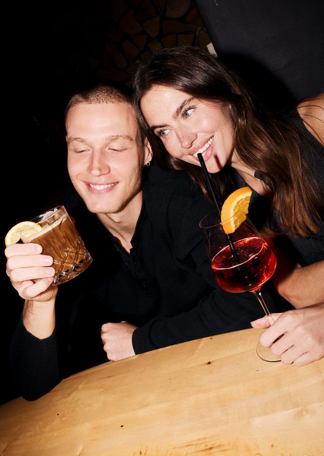 Laughing couple with cocktails at the bar