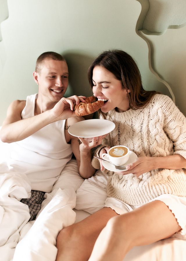 Couple having breakfast in bed with croissants and coffee